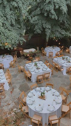 an outdoor dining area with tables and chairs set up for a formal dinner in the garden