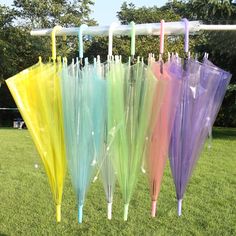 there are many umbrellas hanging on the line in the grass, one is multicolored