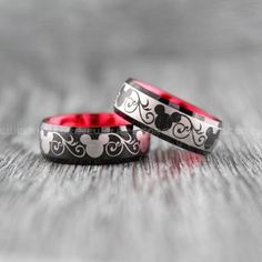 two rings with mickey mouse designs on them sitting on top of a wooden table next to each other