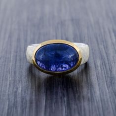 This ring is one of a kind fully made of 925 sterling silver with high quality craftsmanship.  The band which is main highlight of the ring , as its has a matte scratched design band which is done very professionally and takes time. The collet is of pure solid gold vermeil which gives ring a two tone look. Gemstone: Natural Tanzanite AAA quality 10 carat / 11mm x 15mm Facts About Vermeil Jewelry: Is gold vermeil good quality? After solid gold, gold vermeil is the highest quality type of gold ton Modern Tanzanite Gemstone Ring, Timeless Tanzanite Rings For Gifts, Timeless Tanzanite Rings As Gift, Timeless Silver Tanzanite Jewelry, Formal Sterling Silver Cabochon Sapphire Ring, Formal Cabochon Sapphire Ring In Sterling Silver, Polished Tanzanite Jewelry For Anniversary, Polished Tanzanite Sapphire Ring, Oval Tanzanite Jewelry With Polished Finish