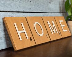 a wooden block with the word home on it sitting next to a potted plant