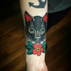 a black cat with flowers on its arm and an arrow tattoo design on it's wrist