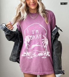 "I'm Okay Shirt, Skeleton Shirt, Halloween Horror Shirt, Oversized Tshirt, Comfort Colors Tshirt, Plus Size Halloween Shirt, Graveyard Shirt Whether you're hitting the road for a cross-country adventure or just hanging out with friends, you'll love its comfortable, oversized fit with this Comfort Colors shirt. The mineral wash feel is super soft and perfect for any casual occasion. Rock this tee with your favorite jeans or leggings and you'll look great no matter what. This is a standard unisex size Comfort Colors Tee. For an oversized tee, please size up. If you are looking for an oversized \"T-shirt Dress\" look, we recommend sizing up 2 sizes. Please review the size chart to ensure you receive the fit you want. HOW TO ORDER 1- Select \"Shirt Size\". 2- Select quantity. 3- Click \"Add To Halloween Tops With Letter Print In Loose Fit, Trendy Oversized Tops For Halloween, Oversized Screen Print Top For Halloween, Spooky Crew Neck Top With Relaxed Fit, Fall Grunge Shirt With Letter Print, Oversized Screen Print Tops For Halloween, Grunge Letter Print Shirt For Fall, Spooky Relaxed Fit Top With Letter Print, Fall Grunge Letter Print Shirt