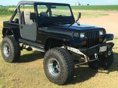 a black jeep parked on top of a grass covered field