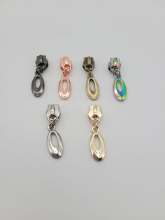 six different colored metal clips on a white surface