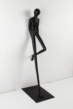 a black statue is standing in front of a white wall