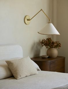 a white bed sitting next to a wall mounted lamp