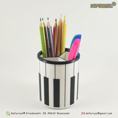 pencils and markers are in a black and white pen holder on a white background