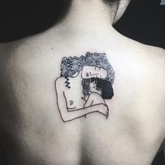 a woman's back with a tattoo of a man hugging her on the shoulder