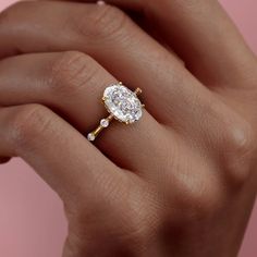 a woman's hand holding an engagement ring with a diamond in the center and two diamonds on each side