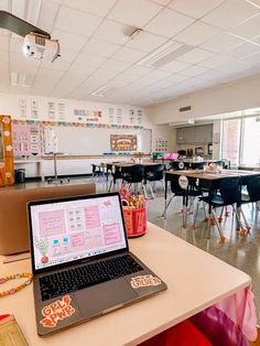 an open laptop computer sitting on top of a table in a room filled with tables and chairs