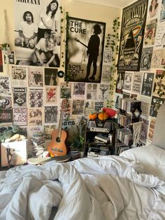 an unmade bed in a bedroom with posters on the wall