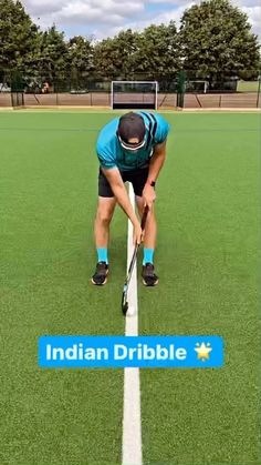 a man bending over on top of a field holding a hockey stick in his hands