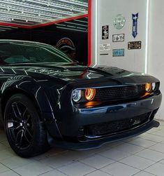 a black sports car is parked in a garage with its hood up and lights on