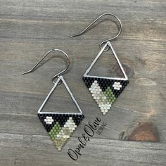 the earrings are made out of black and white mosaic tiles, with silver triangles hanging from them