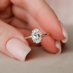 a woman's hand holding an engagement ring with a diamond in the middle, on top of her finger