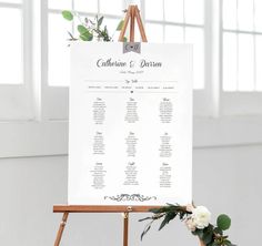 an easel with a seating chart on it and flowers in vases next to the easel