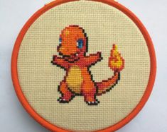 a cross stitched pokemon character on an orange hoop