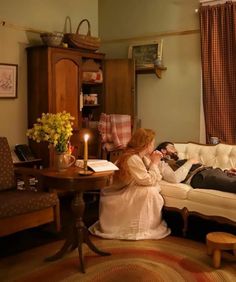 two people sitting on a couch in a living room next to a table and chair