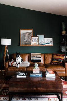 a dog sitting on top of a couch in a living room next to a coffee table