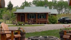 there is a small cabin in the back yard with chairs and fire pit on the lawn