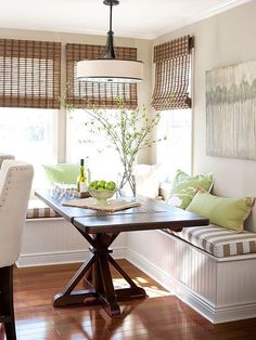 a dining room table and bench with green pillows