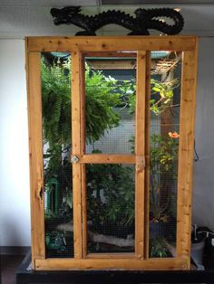 a large wooden cabinet sitting in the middle of a room with plants on top of it