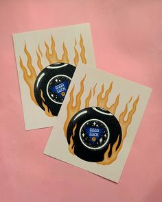 two stickers with flames on them are sitting next to each other in front of a pink background