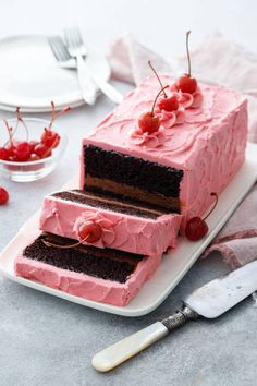 there is a cake with pink frosting and cherries on it