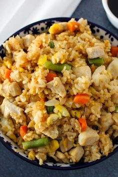 a bowl filled with rice and vegetables next to a cup of coffee