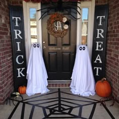 two halloween decorations on the front door of a house with ghost faces and pumpkins