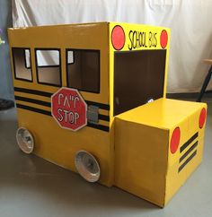 a cardboard school bus made to look like it is painted yellow and has a stop sign on the door