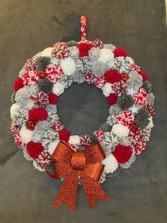 a christmas wreath with red, white and grey pom - poms