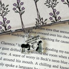 an open book with flowers on it and a keychain hanging from the front