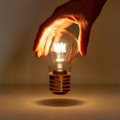 a person is holding a light bulb with their hands on the top and bottom of it