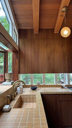 a kitchen with wood paneling and tile counter tops in front of a large window