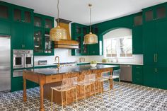 a large kitchen with green cabinets and an island in the middle, surrounded by stools