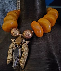 Wow! High End Luxury Ethnic Vibe Statement Necklace Pendant featuring beads ranging in size from 1.5 to 2". Because the beads are handmade, there are imperfections which make them more valuable to collectors. Shown here at a length of 21" but wears more like 19". Closes with gold tone hardware and a fancy lobster claw clasp. If requested, I can add an extender chain free of charge. The 4" x 2.75" pendant features two Tibetan Brass Repousse Peacocks with inlaid Orthoceras Fossil and tigers eye. Two huge Ethiopian hand forged copper beads flank the pendant. Wear alone or layer with coral, turquoise, chrysocolla or warm metals. The perfect statement piece for added drama. Luxury Large Bead Amulet Jewelry, Luxury Beaded Necklace With Lobster Clasp, Artisan Large Beads For Jewelry Making, Artisan Oval Bead Necklace For Festivals, Artisan Necklace With Oval Beads For Festivals, Handmade Artisan Amber Beaded Necklaces, Artisan Gemstone Beads For Festivals, Artisan Festival Necklace With Oval Beads, Handmade Artisan Amber Beaded Necklace