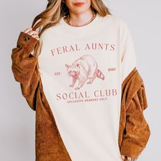 Welcome your a soon-to-be aunt with this feral aunts social club personalized pregnancy reveal shirt! This stylish t-shirt is perfect for announcing the big news. With a fun and trendy design, this custom shirt makes a fantastic gift for your sister, bestie, or sister-in-law and a memorable way to share your pregnancy reveal with the family. Whether it's for a special occasion or just to surprise her, this shirt is sure to make her feel special and excited about her new role as the coolest aunt Pregnancy Reveal To Family, Pregnancy Reveal Shirt, Raccoon Shirt, Aunt Shirt, Auntie Shirts, Aunt Shirts, Gifts For Your Sister, Pregnancy Reveal, Pregnancy Reveals