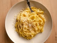 a white bowl filled with pasta and parmesan on top of a wooden table