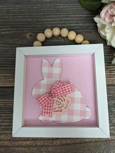 a pink and white frame with a wooden bunny on it