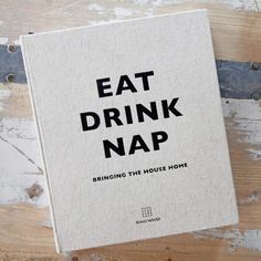 a book sitting on top of a wooden floor next to a pair of scissors with the words eat drink nap printed on it