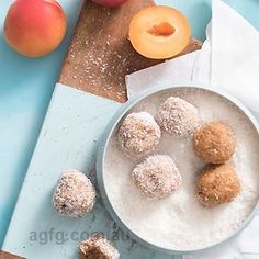 a bowl filled with sugar covered donuts next to peaches