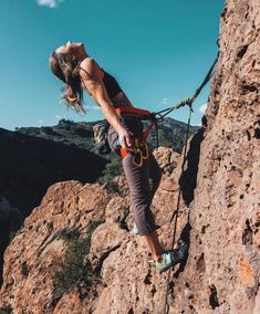 a woman climbing up the side of a mountain