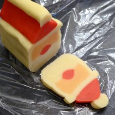 two slices of cake sitting on top of plastic wrapper covered in red and yellow icing