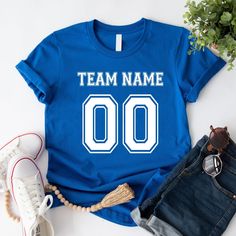 a t - shirt that says team name 00 on it next to some jeans and shoes