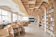 children are sitting in the library with bookshelves lined up against the wall and on the floor