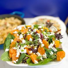 a salad with oranges, feta cheese and spinach leaves on a white plate