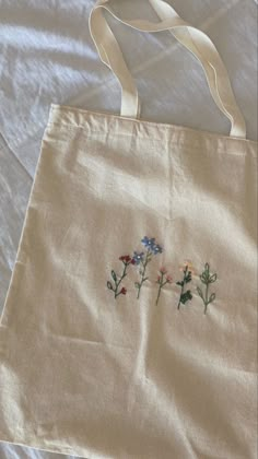 a white bag with embroidered flowers on it