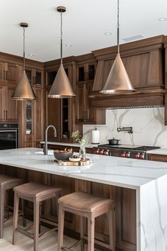 a large kitchen with wooden cabinets and marble counter tops, an island with stools